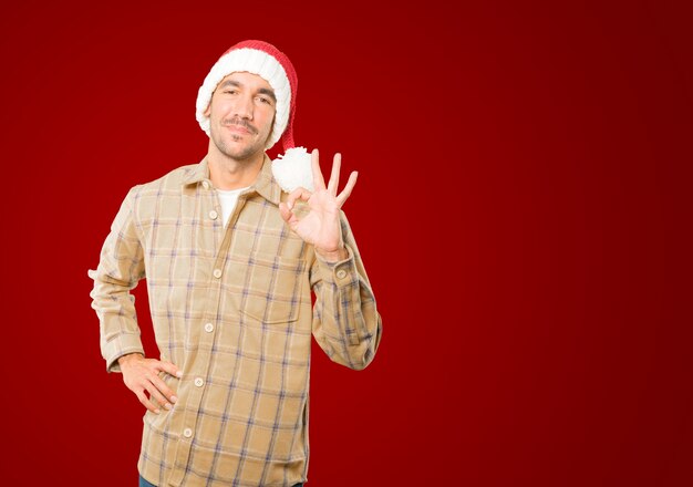 Hombre joven con sombrero de Navidad gesticulando