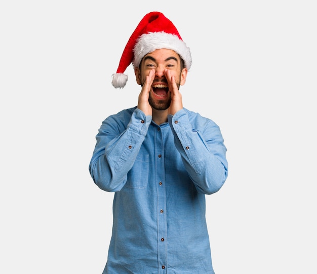 Hombre joven con sombrero de santa gritando algo feliz al frente