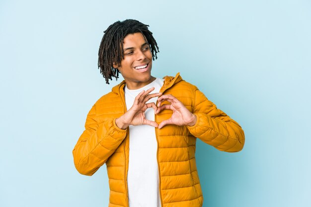 Hombre joven sonriendo y mostrando una forma de corazón con las manos.