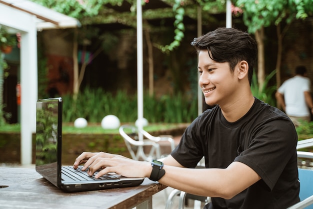 Hombre joven sonriente que usa la computadora portátil
