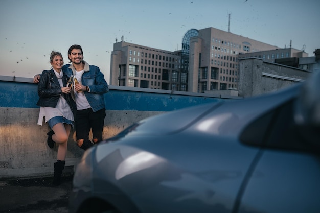 Hombre joven y su novia descansando en el estacionamiento de la azotea