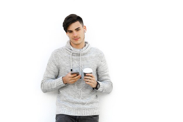 Hombre joven con suéter gris sobre pared blanca