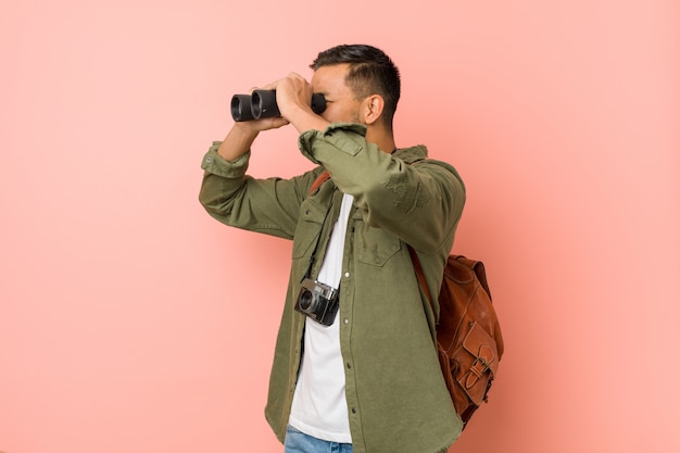 Hombre joven del sur de Asia mirando a través de un binoculares.