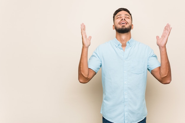 Hombre joven del sur de Asia que grita al cielo, mirando para arriba, frustrado.