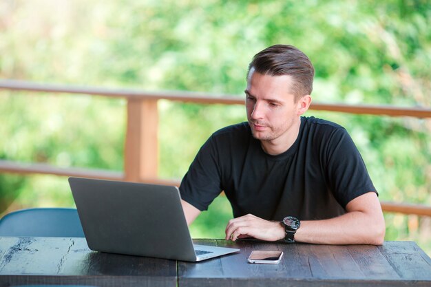 Hombre joven con teléfono celular al aire libre en la cafetería al aire libre. Hombre con teléfono inteligente móvil.