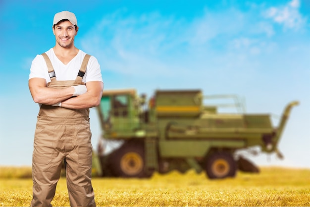 Hombre joven trabajador en el campo, cosechadora en segundo plano.