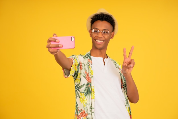 Hombre joven turista tomando autorretratos con un teléfono móvil.