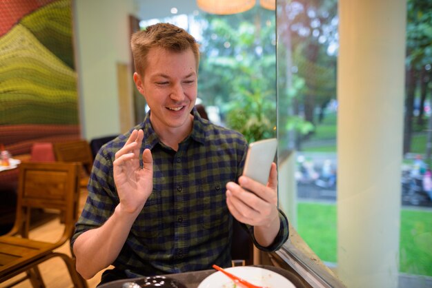 Hombre joven turista vlogging con teléfono móvil en restaurante