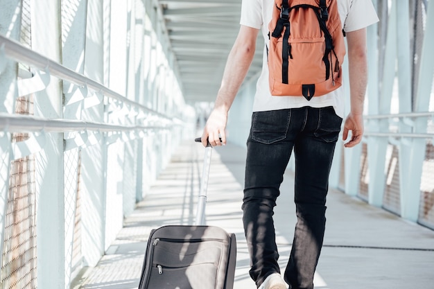 Hombre joven viajero en la estación de tren. Concepto de viaje Foto, bolso, maleta caminando para viajar, fotos modernas y brillantes, espacio de copia