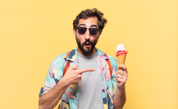 Hombre joven viajero loco apuntando o mostrando y sosteniendo un helado