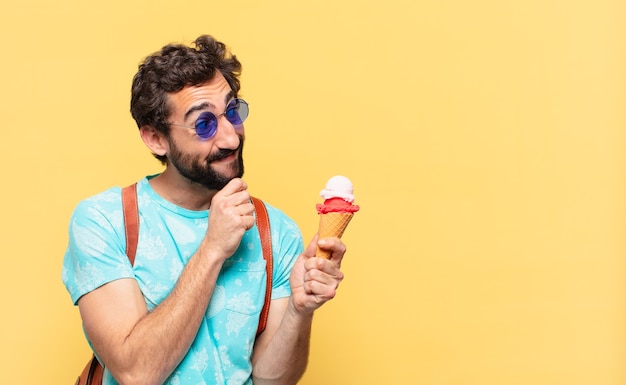 Hombre joven viajero loco pensando en la expresión y sosteniendo un helado