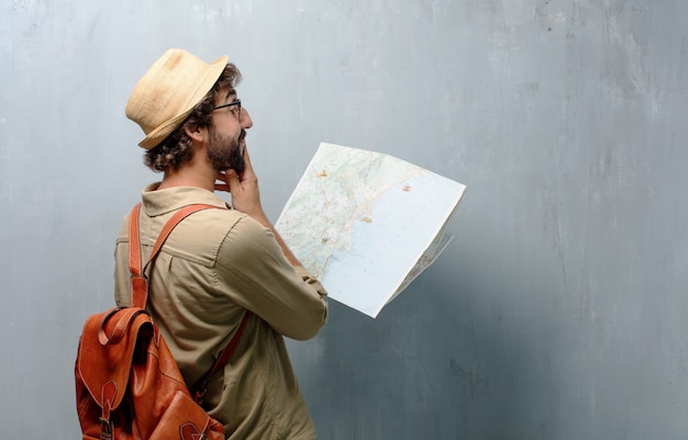 Foto hombre joven viajero con un mapa y bolso de piel.