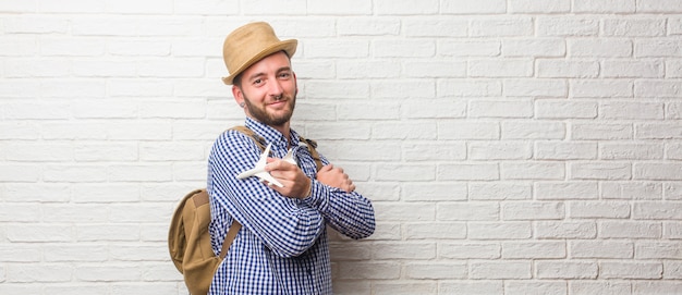 Hombre joven viajero con mochila y una cámara vintage orgullosa y segura, apuntando aleta