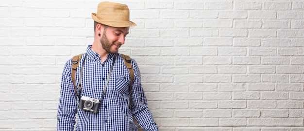 Foto hombre joven viajero con mochila y una cámara vintage riendo y divirtiéndose, relajado y alegre.