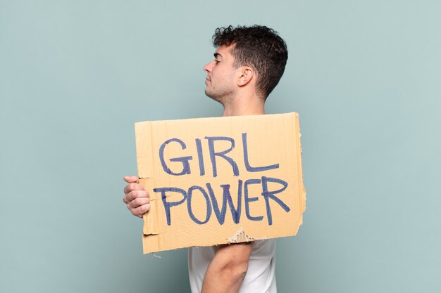 Foto hombre joven en vista de perfil con cartel con texto: girl power
