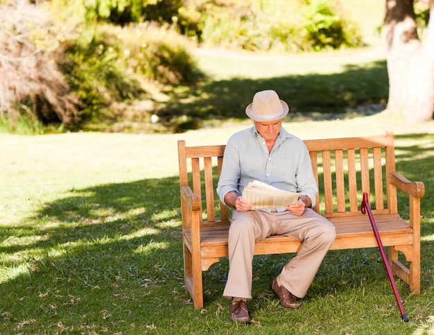 Hombre jubilado leyendo su periódico en el banco