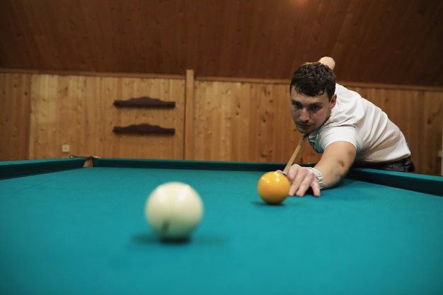 El hombre juega al billar y apunta antes del turno.