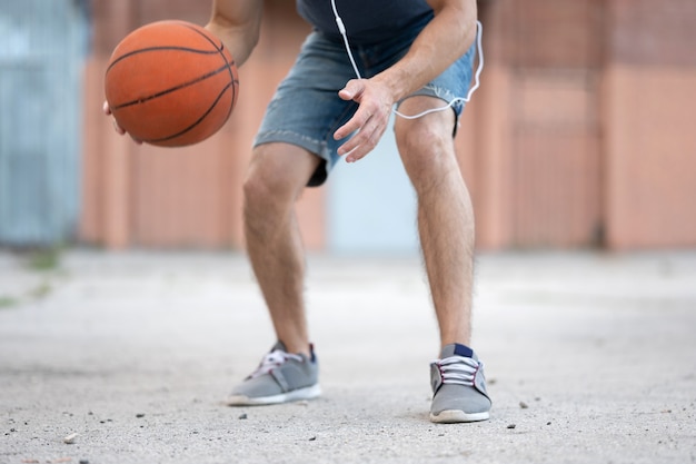 Un hombre juega baloncesto en el patio de la calle durante el día.