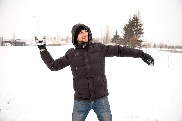Un hombre juega a las bolas de nieve y sonríe lanza a la persona de la nieve