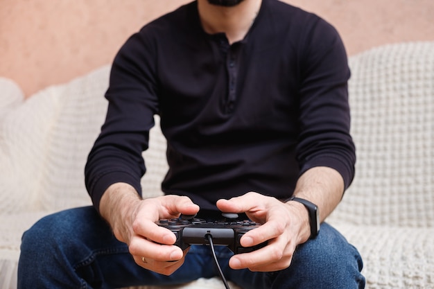 Un hombre juega videojuegos con un joystick en sus manos.