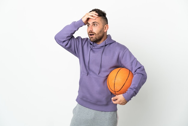 Hombre de jugador de baloncesto aislado en la pared blanca haciendo gesto de sorpresa mientras mira hacia el lado