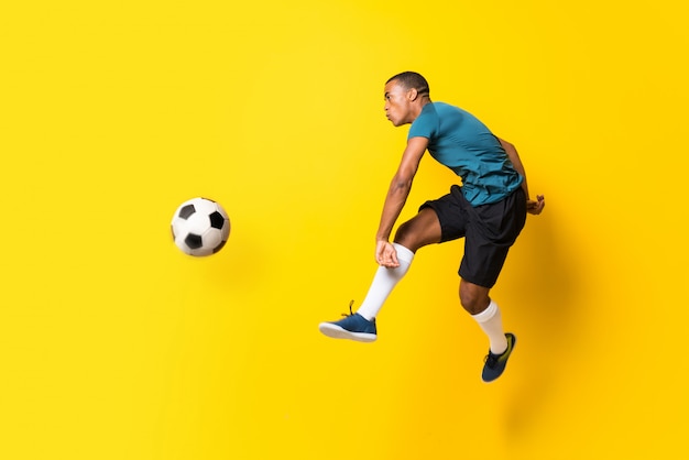 Hombre de jugador de fútbol americano afro sobre pared amarilla aislada