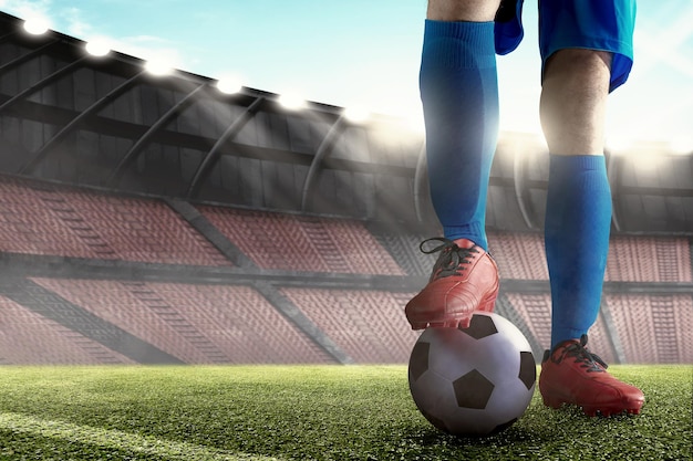 Hombre jugador de fútbol con una camiseta azul de pie con la pelota