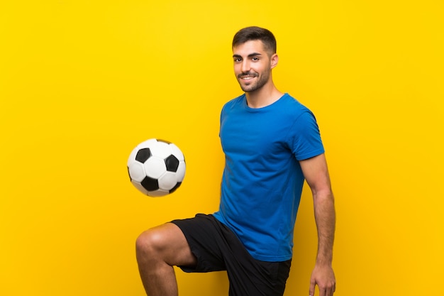 Hombre de jugador de fútbol guapo joven sobre pared amarilla aislada