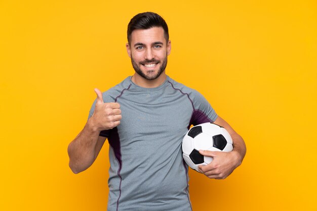 Hombre de jugador de fútbol sobre pared aislada con pulgares arriba porque algo bueno ha sucedido