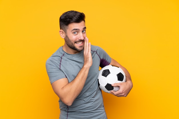 Hombre de jugador de fútbol sobre pared aislada susurrando algo