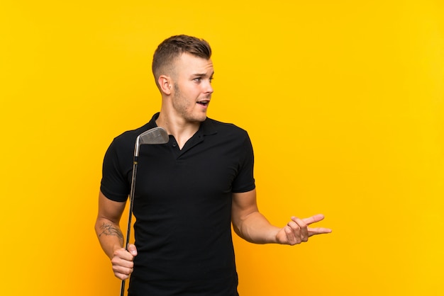 Hombre jugador de golfista sobre pared amarilla aislada con expresión facial sorpresa
