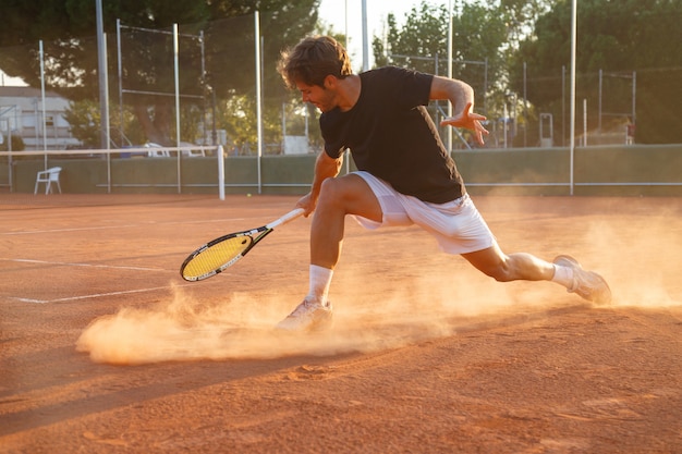 Foto hombre de jugador de tenis profesional jugando en la cancha en la tarde.