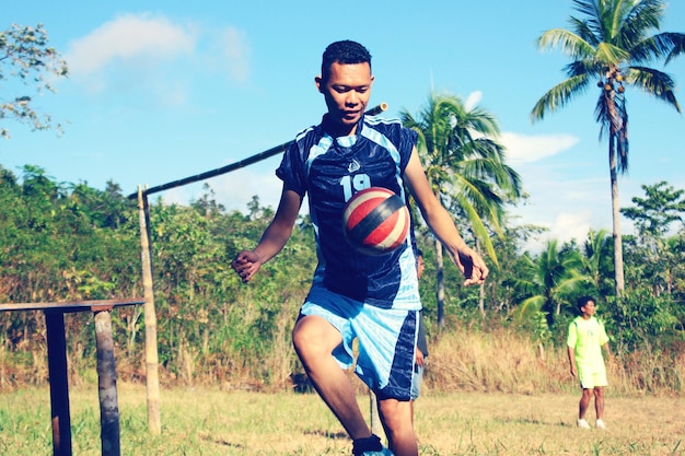 Hombre jugando al fútbol contra árboles en el campo