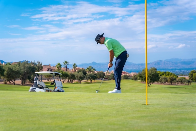 Hombre jugando al golf golpeando la pelota en el green con el putter