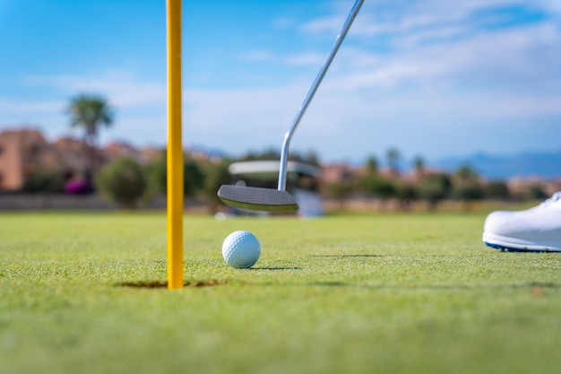 Hombre jugando al golf metiendo la pelota en el hoyo del green con el putter