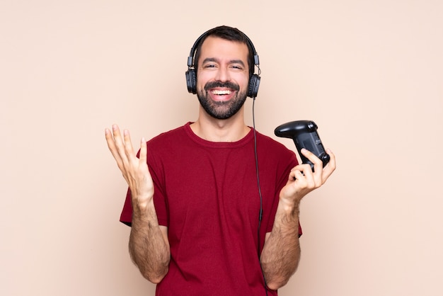 Hombre jugando con un controlador de videojuego sobre pared aislada sonriendo mucho