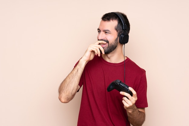 Hombre jugando con un controlador de videojuego sobre pared aislada sonriendo mucho