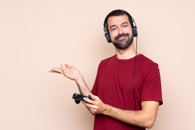 Hombre jugando con un controlador de videojuegos sobre la pared extendiendo las manos a un lado para invitar a venir