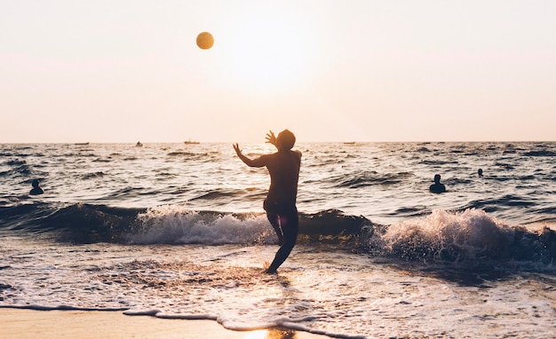 Hombre jugando con la pelota en el mar contra el cielo