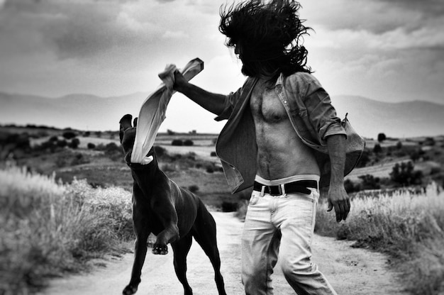 Hombre jugando con perro en el campo contra el cielo