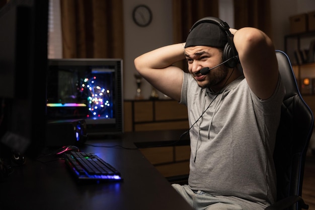 Un hombre jugando profesionalmente en una computadora con auriculares