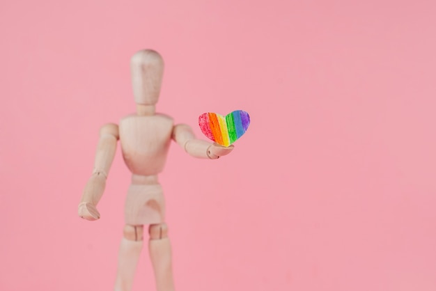 Hombre de juguete de madera con un corazón de papel de arco iris