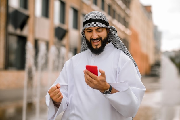 Hombre en kaffiyeh y thobe con un teléfono en las manos