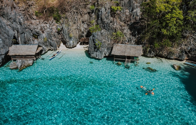 Hombre en kayak en la laguna gemela entre las rocas y las casas de pescadores, disfrutando del paisaje. Concepto sobre viajes en filipinas