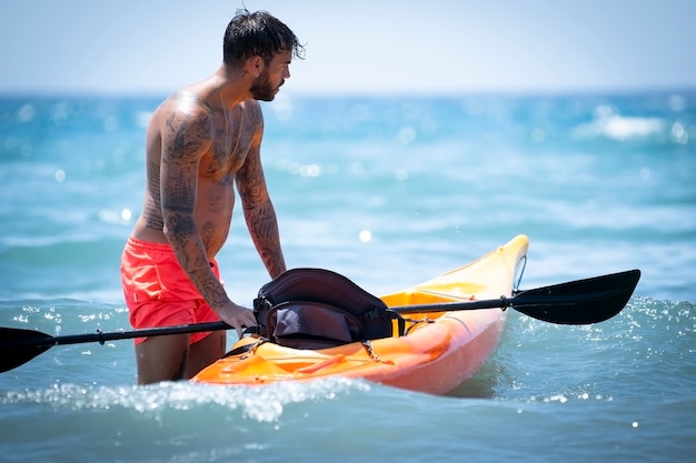 Hombre en kayak en la playa durante las vacaciones de verano