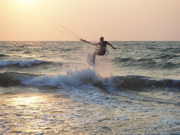 Un hombre kitesurf cerca de la costa al atardecer.