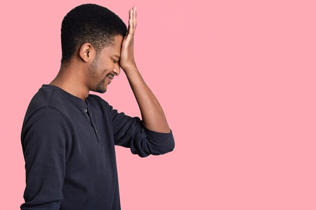 El hombre de lado se da cuenta de su error, mantiene la mano en la frente, se viste con ropa casual, se arrepiente de algo, se viste con un jersey informal, aislado en una pared rosa con espacio en blanco para el texto.