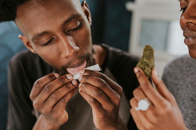 Un hombre lamiendo un porro de marihuana