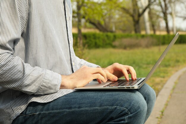 Hombre con laptop trabaja en el parque. Trabajo al aire libre