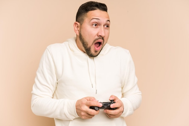 Hombre latino adulto jugando con un controlador de juego aislado